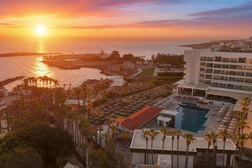 an aerial view of a hotel and the ocean at sunset at Cavo Maris Beach Hotel & Suites in Protaras