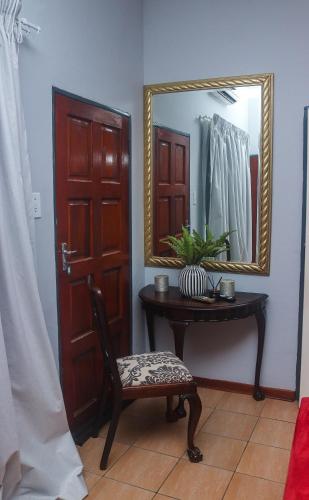 a room with a table and a mirror and a chair at The Well Apartments in Mbabane