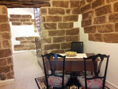 una mesa y sillas en una habitación con una pared de piedra en B&B Colti Di Rosa, en Castelsardo