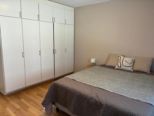a bedroom with white cabinets and a large bed at Huoneisto Vipunen in Savonlinna