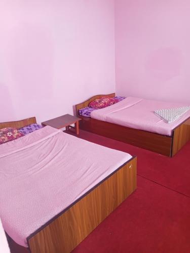 two beds in a room with red carpet at Saura place Homestay in Nagarkot