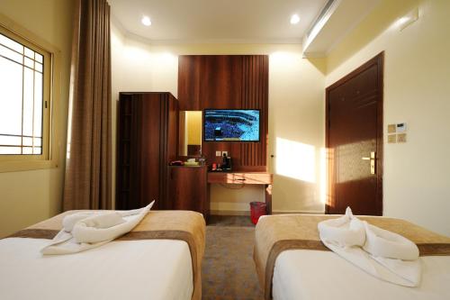 a hotel room with two beds and a television at فندق اللؤلؤة البلاتيني - Platinum Pearl Hotel in Medina