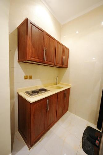 a small kitchen with wooden cabinets and a sink at شقق اللؤلؤة الذهبي - Golden Pearl Apartments in Sīdī Ḩamzah