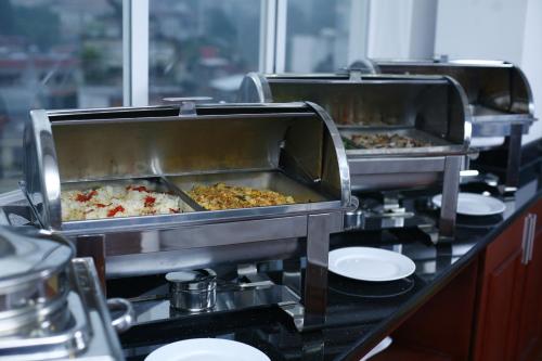 a buffet line with three trays of food at Hanoi Emotion Hotel in Hanoi
