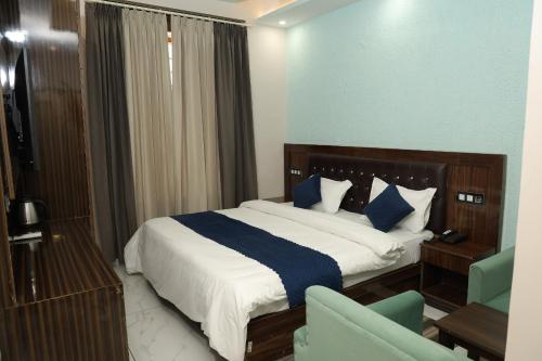 a bedroom with a bed with blue and white sheets at Hotel M Sarthak Dehradun in Dehradun