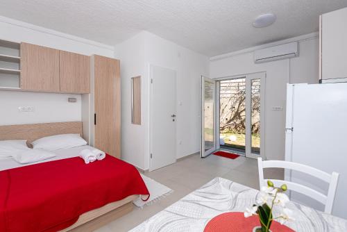 a bedroom with a bed with a red blanket at Apartments Luka in Pag