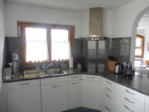 a kitchen with white cabinets and a sink and a window at Apartment Theresli First Floor in Saas-Almagell