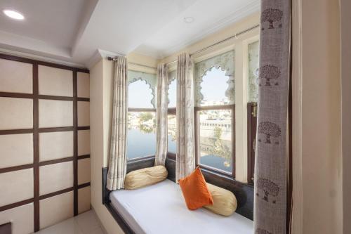 ウダイプールにあるHide-In Udaipur - A Lake View Boutique hotelの部屋の窓際の席にオレンジ色の枕が置かれている