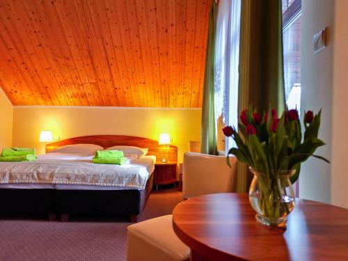 a hotel room with a bed and a table with flowers at Pensjonat Olympia w Przesiece in Przesieka