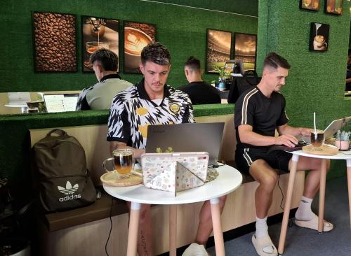 two men sitting at a table with a laptop at Destination Boutique Hotel in Pattaya