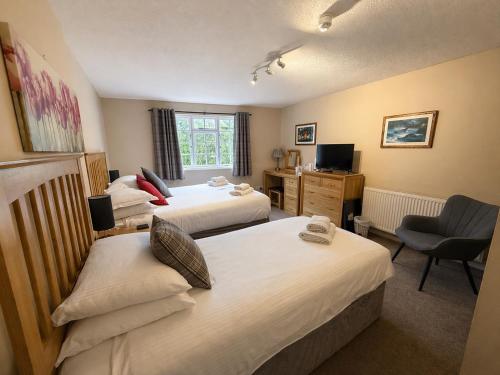 a hotel room with two beds and a chair at The Riverside in Boscastle