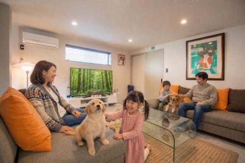 a family sitting in a living room with two dogs at Bito Petrip hotel 美都ペットリップホテル #LP1 in Tuyama