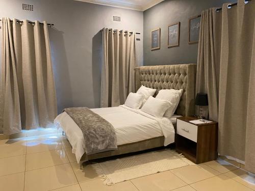 a bedroom with a bed with white sheets and pillows at The Stone Duplex Apartment House 1 in Lilongwe