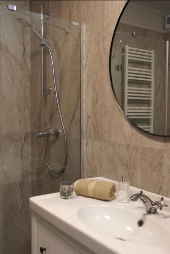 a bathroom with a sink and a shower with a mirror at Downtown Apartments Podpromie Monica with UNDERGROUND PARKING in Rzeszów