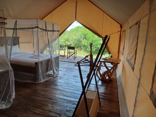 a room with a bed and a hammock in a tent at Veilscape Mara Camp in Masai Mara