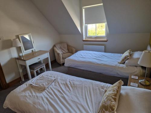 a room with two beds and a desk with a mirror at Sidhean Dubha Holiday Home in Portree