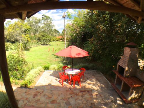 a table and chairs with a red umbrella on a patio at Cabañas La Carolina - Mesa de Los Santos in Los Santos
