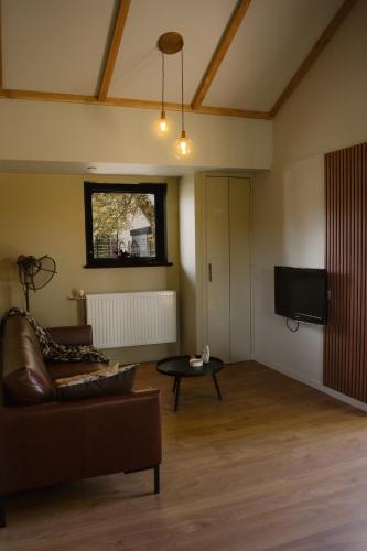a living room with a couch and a tv at B&B de Lytse Geast in Tietjerk