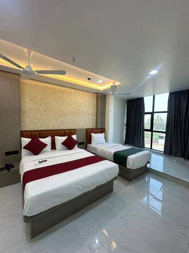 a bedroom with two beds and a large window at Hotel Fortune in Ankleshwar