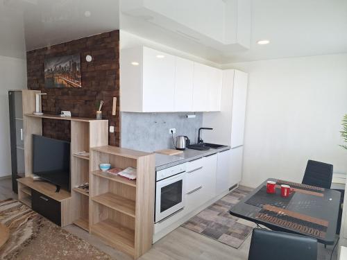 a kitchen with white cabinets and a desk with a laptop at Apartmán s balkonem in Most