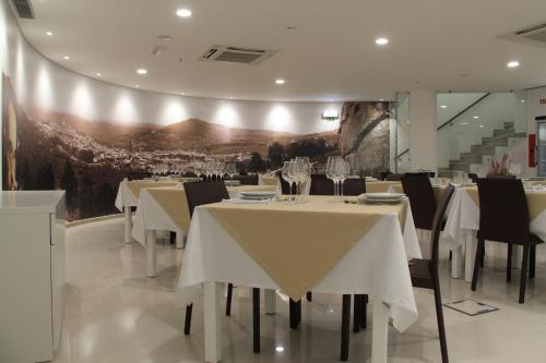 a dining room with white tables and black chairs at Hotel José Régio in Portalegre
