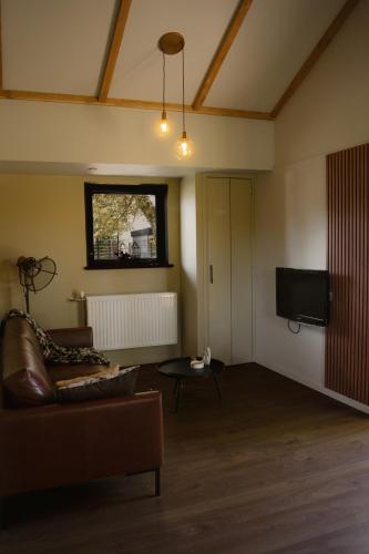 a living room with a couch and a flat screen tv at B&B de Lytse Geast in Tietjerk