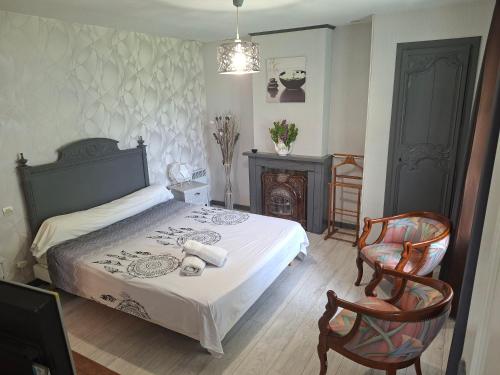 a bedroom with a bed and two chairs and a fireplace at La Ferme aux Canards in Sassetot-le-Mauconduit