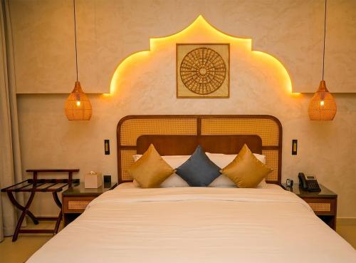 a bedroom with a large bed with pillows at Heritage Inn Hotel Apartments in Al Wakrah