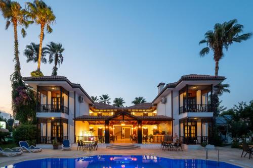 a house with a swimming pool and palm trees at Palma Rosa Hotel in Kemer