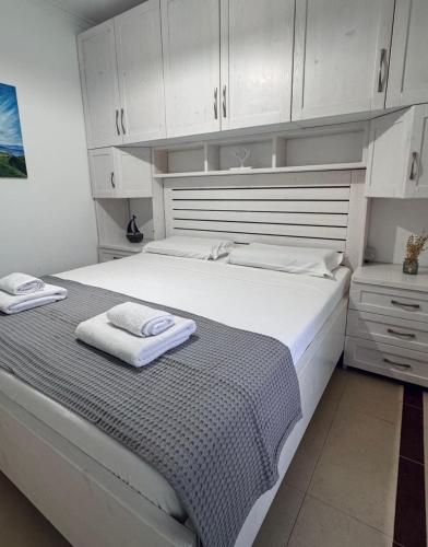 a white bedroom with a large bed with white cabinets at Ioanian Évasion in Vlorë