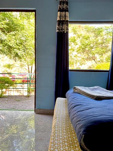 a bedroom with a bed and a large window at Stay Maasa Resort in Shivpuri