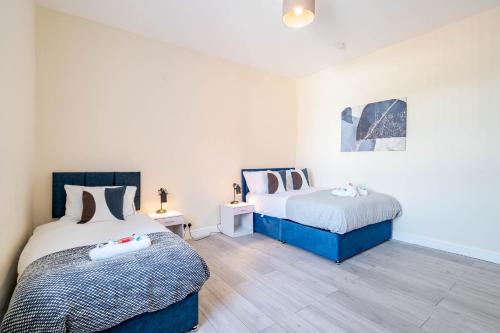 two beds in a room with white walls and wooden floors at 3 Bedroom House in Rishton by Eason Stays, Great Location Near Shops & Transport in Rishton