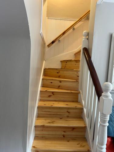 a staircase with wood floors and white walls at Kilpedder cottage in Kilpedder