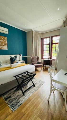 a bedroom with a bed and a couch and a chair at Hidden Villas Guesthouse in East London