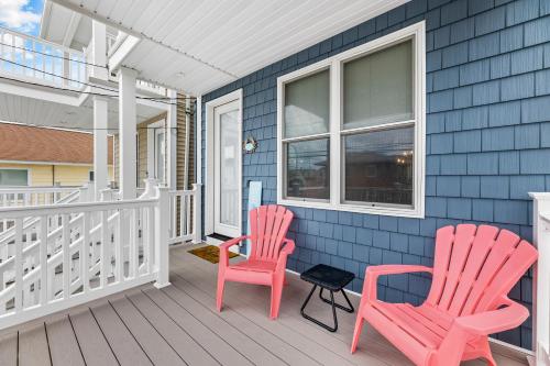 two chairs on the front porch of a blue house at Cozy Shoregri La! - Beach block! in Seaside Heights