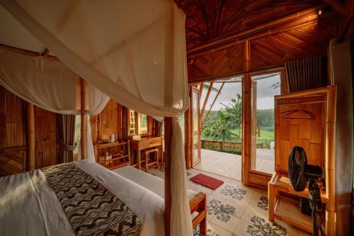 a bedroom with a canopy bed and a balcony at Bambu Teras Viewpoint in Karangasem