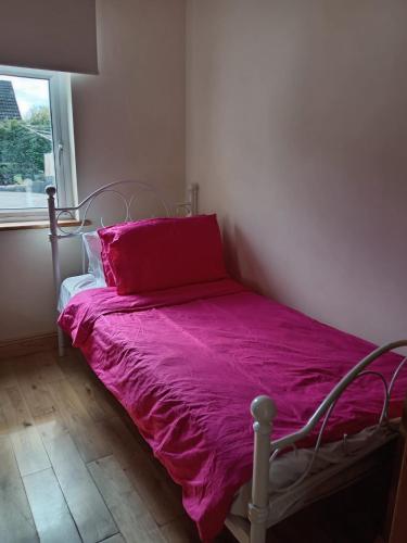 a bedroom with a bed with a pink comforter and a window at Stickens Apartment in Naas