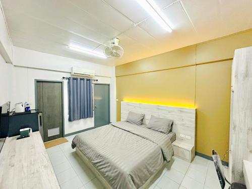 a bedroom with a bed and a yellow wall at H-Hub BBT in Ban Khlong Yuan