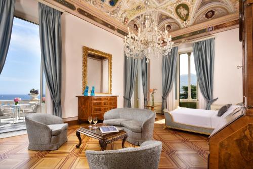 a bedroom with a bed and two chairs and a chandelier at Imperiale Palace Hotel in Santa Margherita Ligure