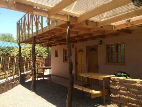 a wooden pergola with a bench and a table at Refugio Don Natu in San Pedro de Atacama