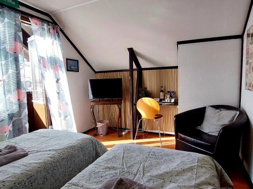 a bedroom with a bed and a chair and a television at Cronin's Guesthouse Bed & Breakfast in Heinola