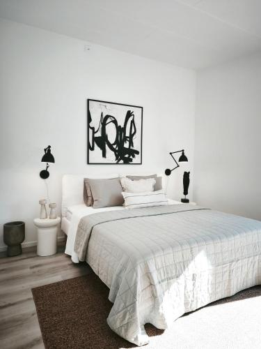 a white bedroom with a large white bed and lamps at Vila Karup Modern Scandinavian Holiday Home in Båstad