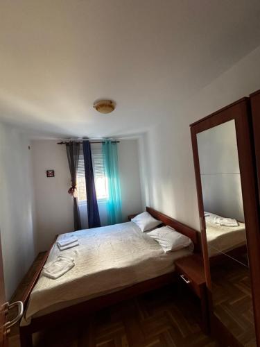a small bedroom with a bed and a mirror at Apartman Tafra1 in Igalo