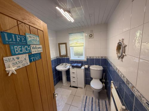 a blue and white bathroom with a toilet and a sink at The Captains Achmelvich in Lochinver