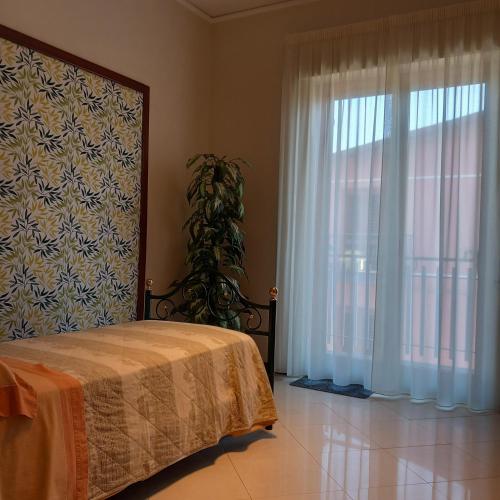 a bedroom with a bed and a large window at New Magnolia House in Belpasso