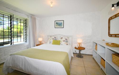 a white bedroom with a bed and a window at Beach Escape in Trou d'Eau Douce
