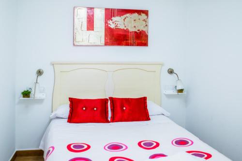 a bedroom with a bed with two red pillows at Apartamento Corralazos in Castril