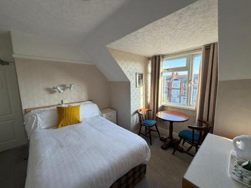 a bedroom with a bed and a table and a window at GNDJ Hotel Skegness in Skegness