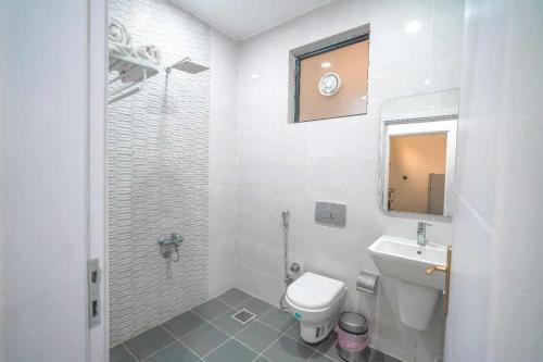 a white bathroom with a toilet and a sink at Danzha Hotel 1 in Erbil