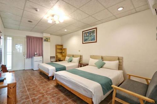 a hotel room with two beds and a chair at Fumigate Hotel in Hengchun South Gate